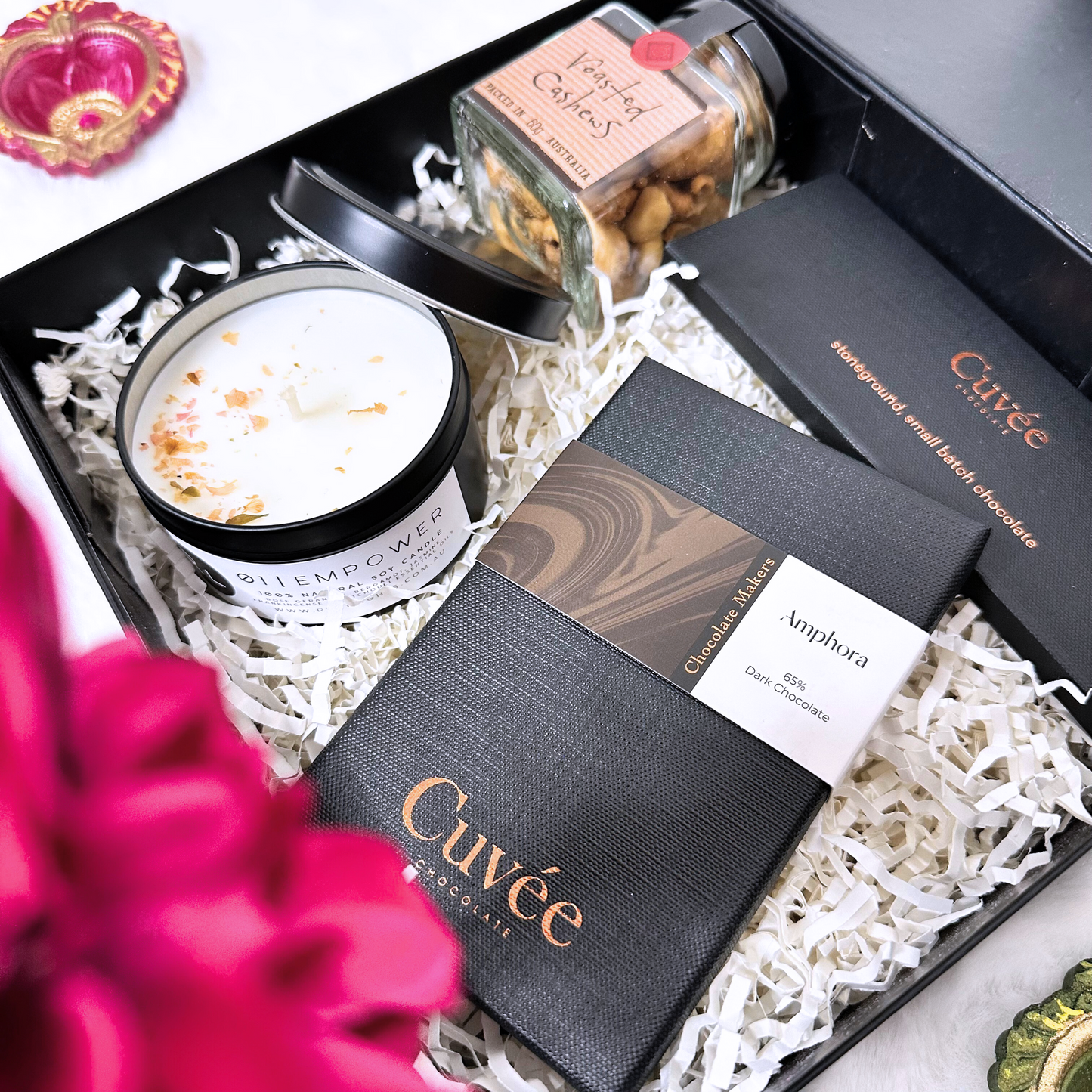 Gift set with Cuveé chocolate, a candle, and a jar of nuts in a decorative box.