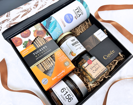 Gift box with various products including a jar of honey, a bottle of tea, and other items.