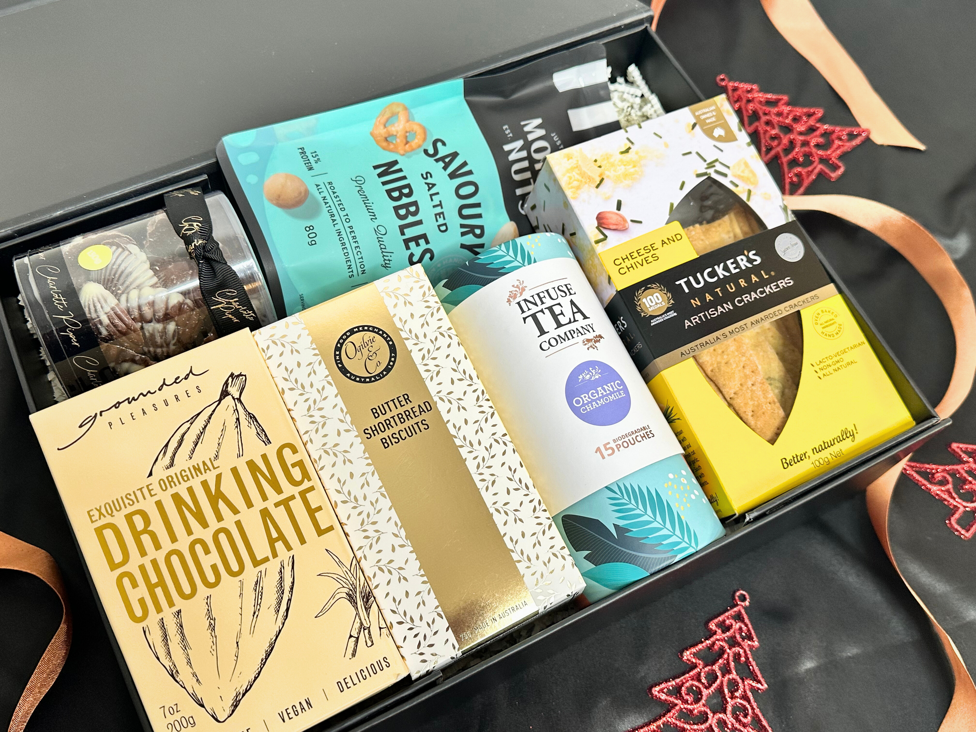 Assorted gourmet food items including drinking chocolate, tea, and crackers in a box.