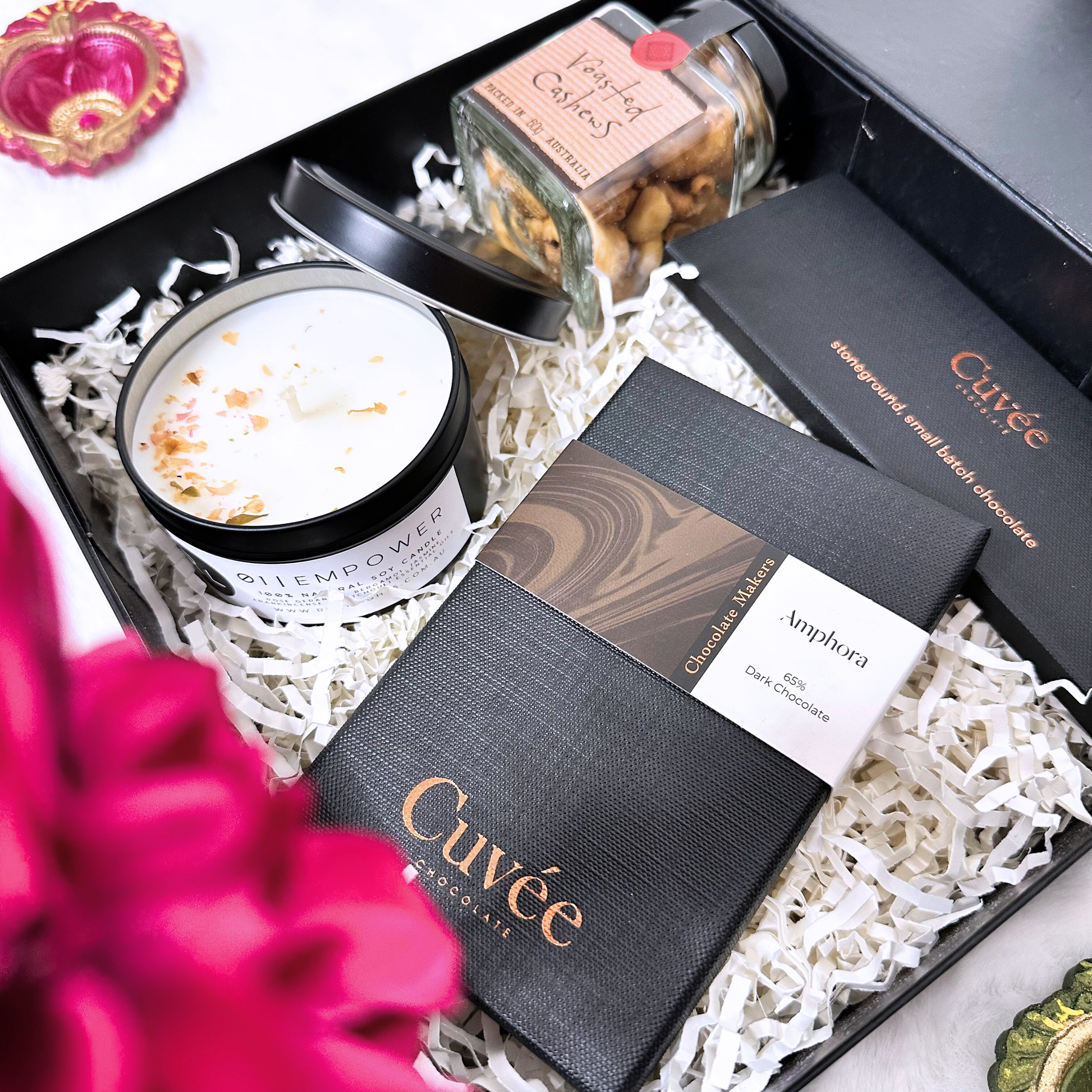 Gift set with Cuveé chocolate, a candle, and a jar of nuts in a decorative box.