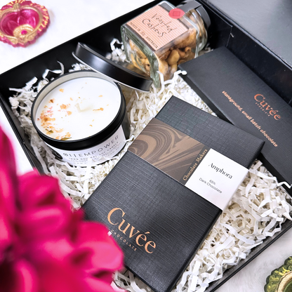 Gift set with Cuveé chocolate, a candle, and a jar of nuts in a decorative box.