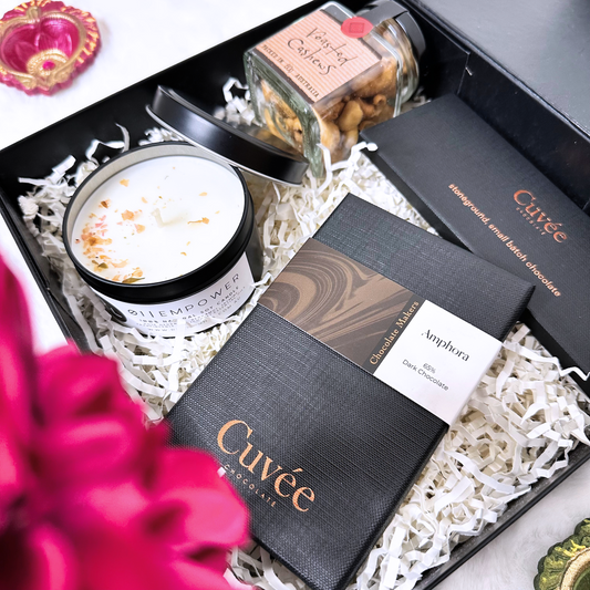 Gift set with Cuveé chocolate, a candle, and a jar of nuts in a decorative box.