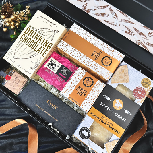 Assorted gourmet food items including drinking chocolate and crackers in a decorative box.