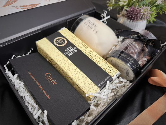 Gift set with chocolate, candles, and other items in a black box.